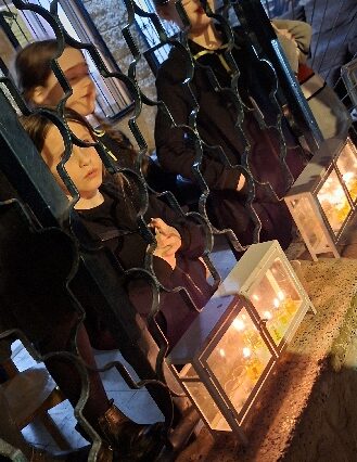 Young religious girls watching the Hannuka candles beyond the window bars, Tzfat