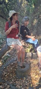 Karmit Arbel sitting and talking over an ancient olive crushing stone, Lost city